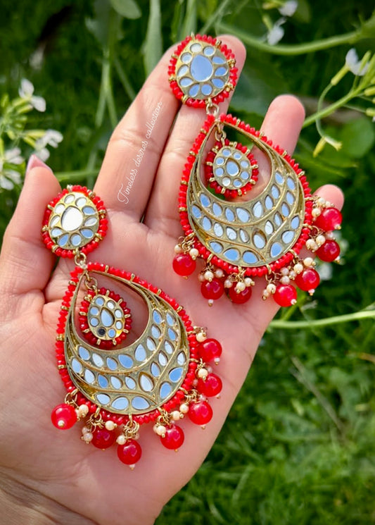 Red earrings in mirror on copper base
